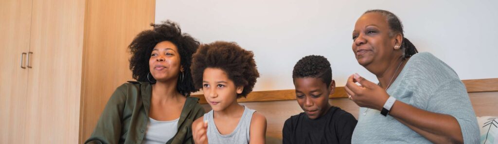avó com a filha e 2 netos assistindo televisão