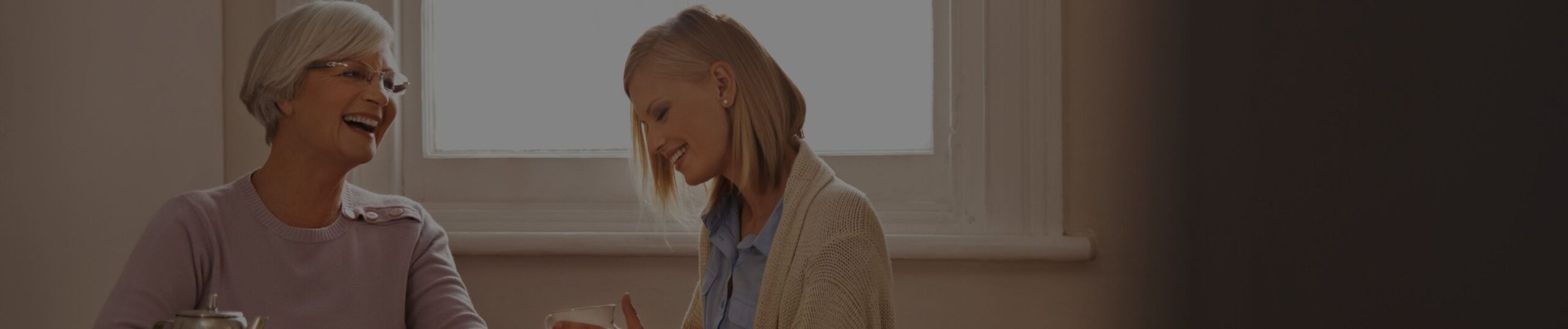 sogra e nora sentadas dentro da casa sorrindo