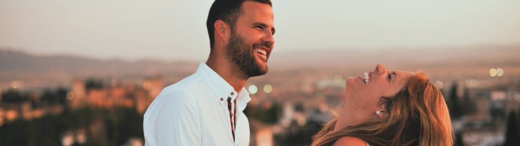 jovem casal em uma vista panorâmica com o homem olhando e a mulher rindo