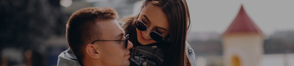 um homem e uma mulher usando óculos de sol se abraçando