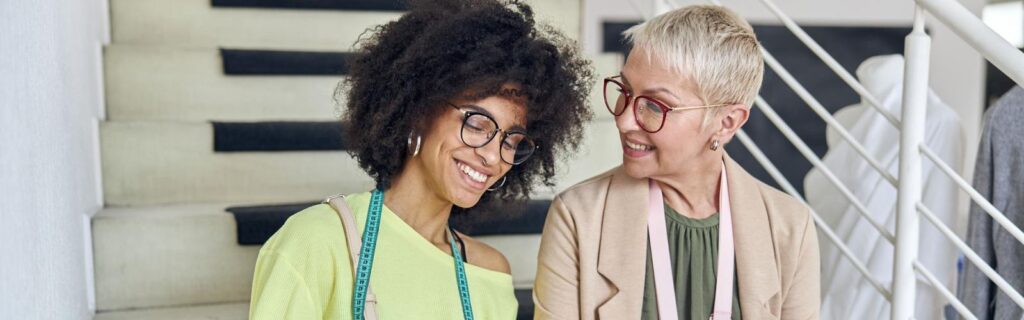 mulher com sua irmã adotiva sentadas em uma sala sorrindo uma para a outra