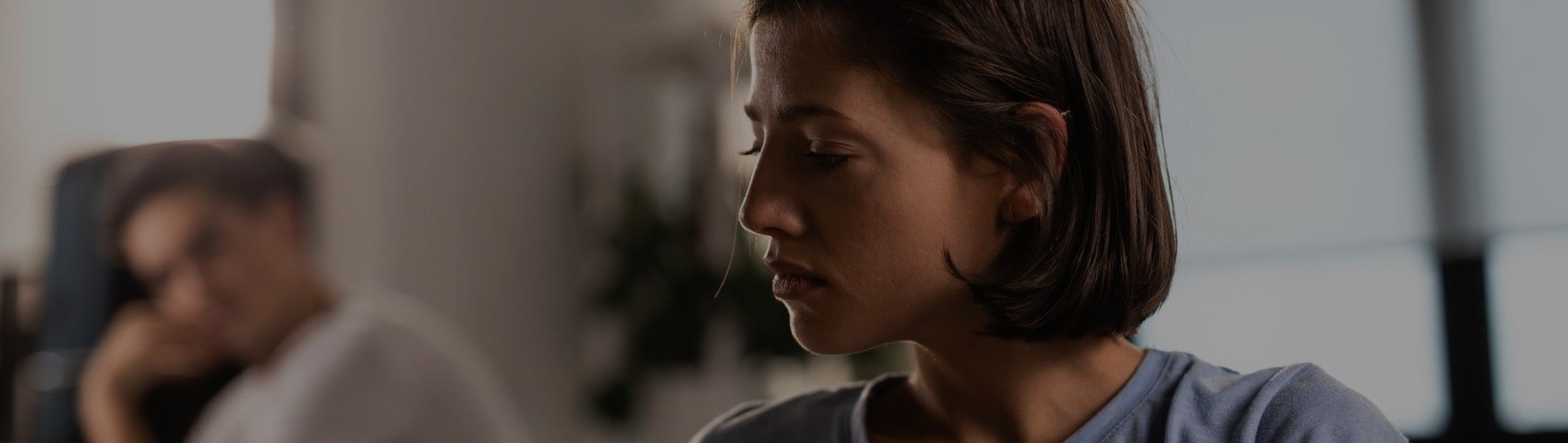 uma mulher triste após a morte de seus pais, e seu marido olhando para ela