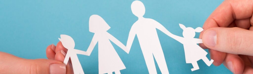 uma pessoa segurando um recorte de papel de uma família unida de mãos dadas