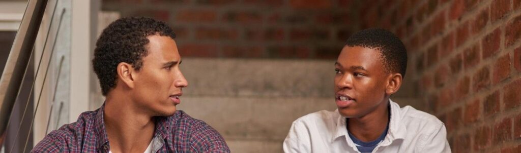 Dois irmãos sentados em uma escada, olhando um para o outro.