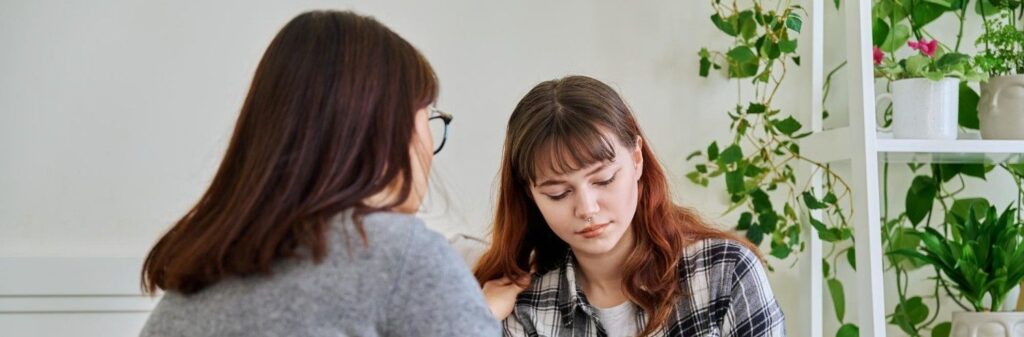 Uma irmã chateada e seu irmão consolando-a.