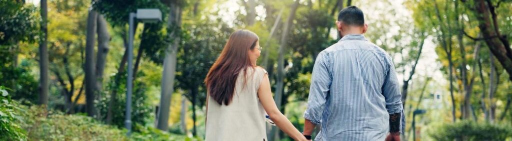 casal caminhando de mãos dadas em um parque