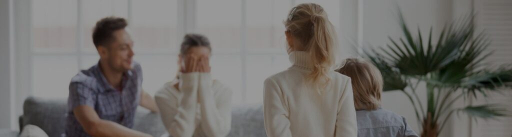 Uma mãe com o marido e os filhos, chorando com as mãos no rosto.