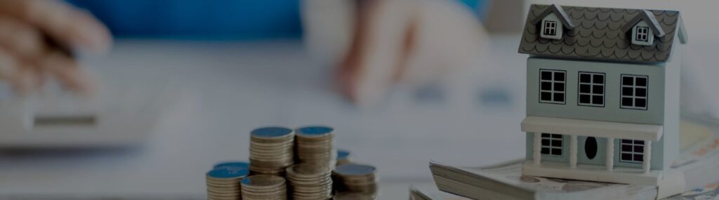 moedas brasileiras sobre uma mesa com uma casa e calculadora